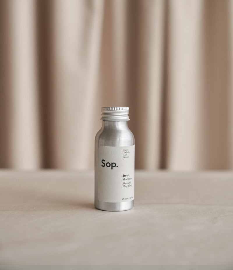 Image shows an aluminium bottle of Sop Smur Shampoo - Neroli and Ylang Ylang 50ml against a light coloured background- Nor–Folk