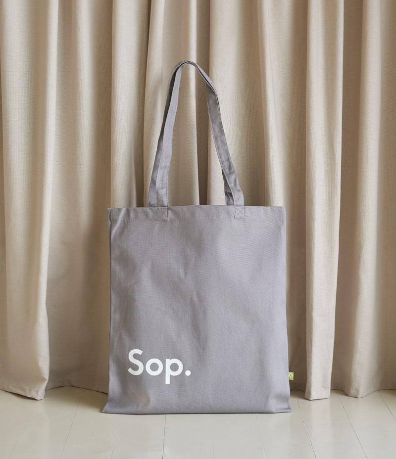 Image shows a grey coloured linen tote bag with a white Sop logo on the bottom left of the bag. Sits against a light coloured background. - Nor–Folk