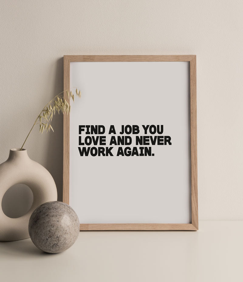 Image shows a wooden frame containing a white print which reads in  black text ' Find a job you love and never work again ' .  To the left of the frame is a ceramic ball and a ceramic vase with a wildflower in. 'Never Work Again' Print - Nor–Folk