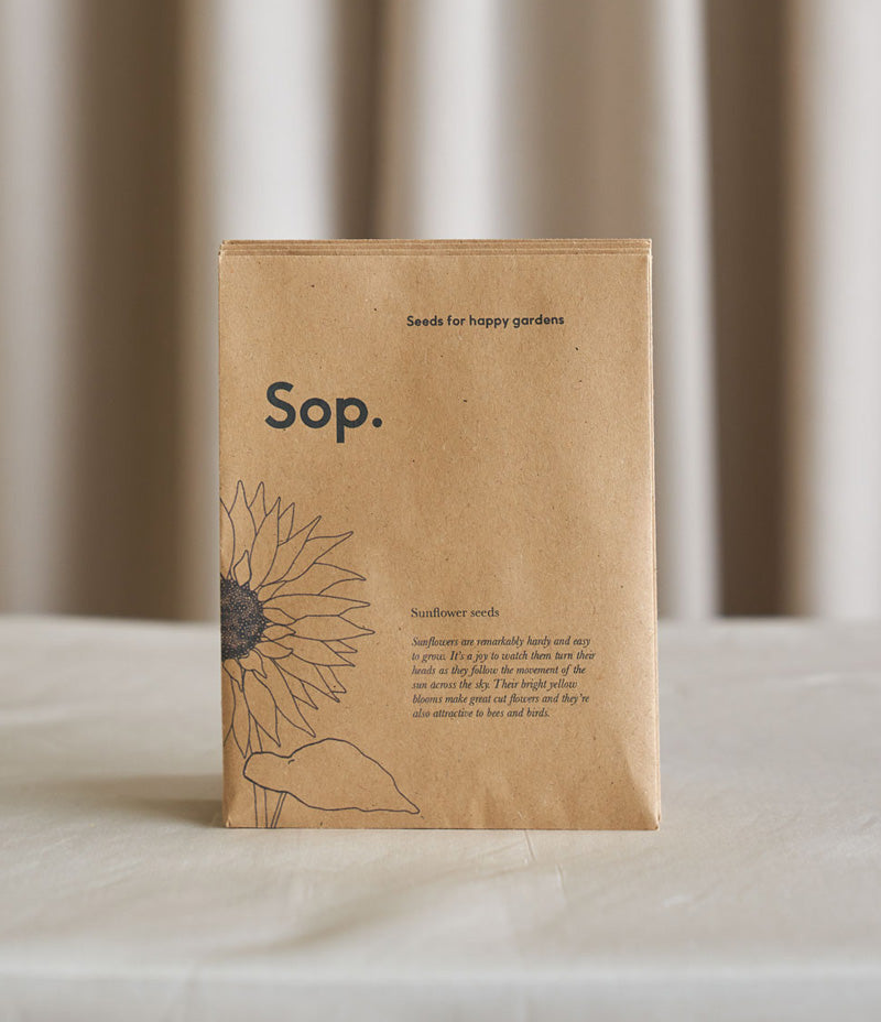 Image shows a packet of Sop – Sunflower Seeds against a light coloured background. The light brown recyled paper packet has an illustration of a sunflower on the left  and a Sop logo . - Nor–Folk
